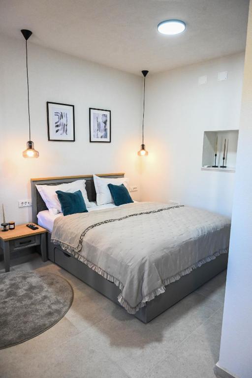 Bedroom with a wide bed, teal cushions and two glass pendant lights